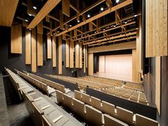 an empty auditorium with rows of seats and wooden beams on the ceiling is lit by spotlights