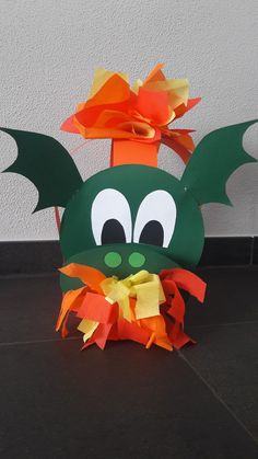 a paper bag with a green dragon on it's head and orange ribbon around its neck