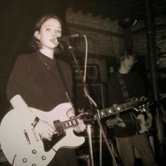 two people are playing guitars and singing into microphones