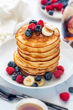 a stack of pancakes with bananas, raspberries and blueberries on a plate