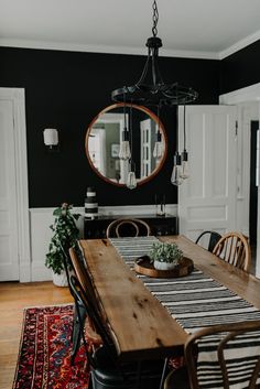 a dining room table with chairs and a potted plant on top of it in front of a round mirror