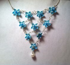 a necklace with blue flowers and pearls hanging from it