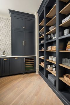 a large kitchen with lots of shelves and cabinets in the center, along with wooden flooring