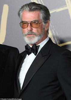 an older man in a tuxedo and bow tie poses for the camera on the red carpet