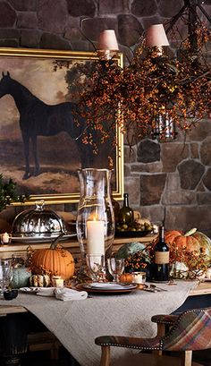 a dining room table is set with candles and pumpkins