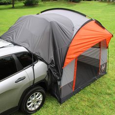 an suv with a tent attached to it parked in the grass