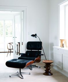 an eames chair and ottoman in a white room