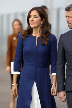 a woman in a blue dress walking next to a man