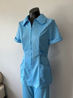 "I have several uniforms like this one in many different colours. Contact me if you are looking for a different colour. This one is in great condition! A land and top vintage suit. There's a hidden zipper down the front. Pocked at each hip and an attached belt that closes at the back with a button. Size: S/M Tag - The Graduate, Uniforms Registered, Made in Canada Era - late 60s/early 70s Top: Bust - 33/34\" Waist - approx 28\" Hips - 35 to 37\" Length - 29\" Pants: Waist - approx 27\" Hips - 35/ Blue Collared Sets With Pockets, Blue Fitted Collared Set, Blue Collared Fitted Sets, Fitted Vintage Blue Set, Blue Fitted Vintage Set, Retro Fitted Blue Sets, Retro Blue Fitted Sets, Vintage Fitted Short Sleeve Sets, 70s Suit