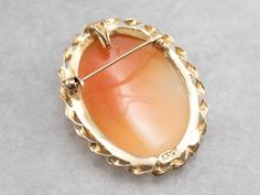 Versatile and lovely, this pin or pendant is beautifully crafted of yellow gold. The framework is a simple twist of polished metal, and the size of this piece lends itself well to wearing day to day as a signature cameo. The color of the shell is a rich, warm tan, and the carved cameo portion is creamy with hints of coral. This pendant does not come with the chain shown. Please feel free to contact us, we will help you find the perfect chain for your style and budget! Metal: 14K Yellow Gold Gem: Senior Stuff, Gold G, Cameo Ring, Cameo Brooch, Cameo Pendant, To Day, Eternity Bands, Estate Jewelry, Vintage Gold