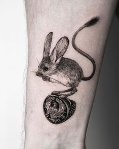 a small mouse tattoo on the left inner forearm and wristband, with an animal in it's center piece