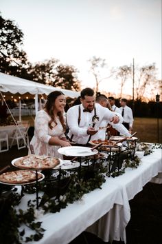 a man and woman standing next to each other at a table with food on it