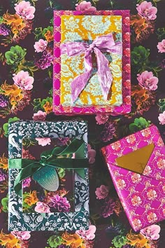 three colorful boxes with bows on them sitting next to each other in front of flowers