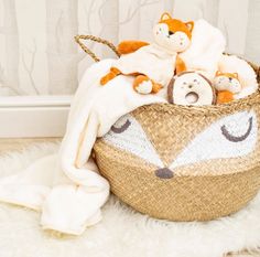 a basket filled with stuffed animals sitting on top of a white rug