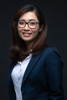 a woman wearing glasses standing in front of a black background