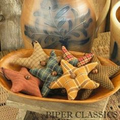 a wooden bowl filled with star shaped ornaments on top of a table next to a vase