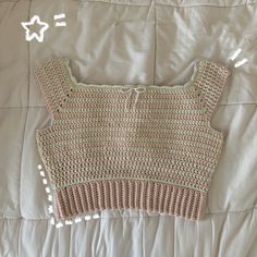 a crocheted sweater laying on top of a white bed with stars above it