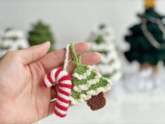 a hand holding a small crocheted ornament with a christmas tree on it