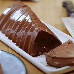 a piece of chocolate cake sitting on top of a white plate next to a knife