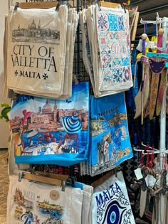 there are many towels hanging up on the rack in this store that is selling souvenirs