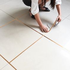 a woman kneeling down on the floor with her legs crossed and holding a pair of scissors