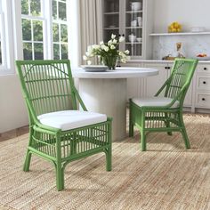 two green chairs sitting in front of a white table