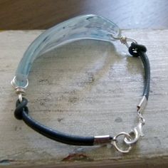 a close up of a bracelet on top of a wooden table with a glass bead