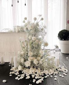 white flowers and candles are arranged on the floor in front of a table with windows