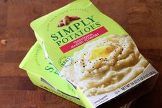 two packages of mashed potatoes sitting on top of a wooden table next to each other