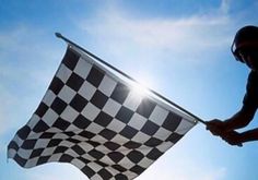 a person holding a checkered flag in front of the sun on a sunny day