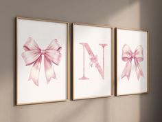 three pink bows are hanging on the wall next to two framed pictures that say nn