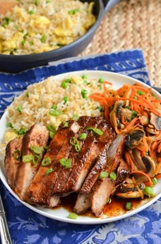 a plate with meat, rice and vegetables on it next to a bowl of salad