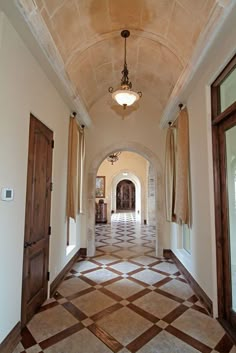 an arched hallway leading to two doors and a chandelier hanging from the ceiling