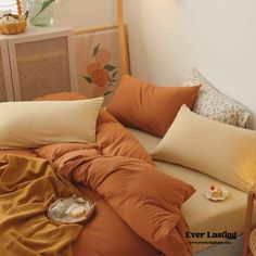 a bed with orange sheets and pillows in a bedroom next to a basket full of flowers