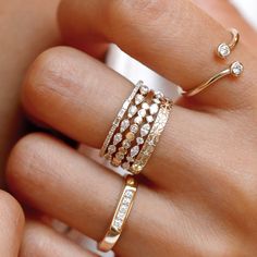 a woman's hand holding three rings with diamonds on each ring and the other