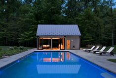 a swimming pool surrounded by lounge chairs next to a house with an open patio and sliding glass doors