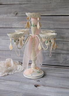 a white candle holder with three candles on it and some pearls hanging from the top