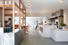 two people are standing at the counter in this modern kitchen with wood and white accents