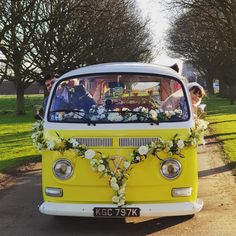 a yellow vw bus decorated with flowers and greenery for a wedding car decoration