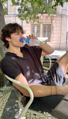 a man sitting in a chair drinking from a water bottle