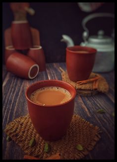 there is a cup of coffee on the table next to some teapots and cups