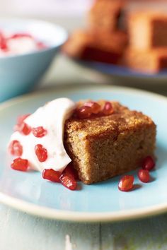 a piece of cake on a plate with whipped cream and pomegranates