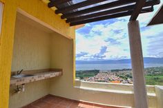 an outdoor kitchen with tiled flooring and yellow walls, overlooking the ocean in the distance