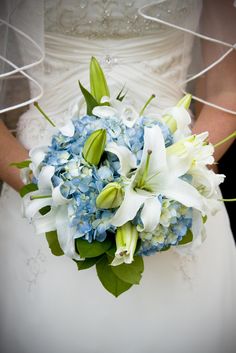 a bride holding a bouquet of blue and white flowers