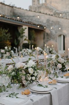 the table is set with white flowers and greenery for an elegant wedding reception in italy