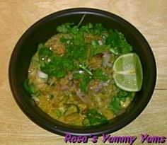 a black bowl filled with food and garnished with cilantro, lime wedges