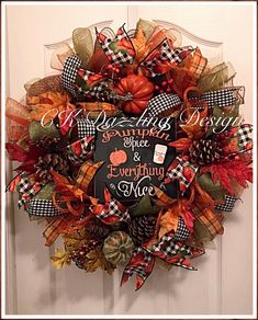 a fall wreath with an orange pumpkin and black checkered ribbon