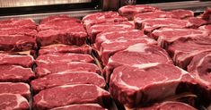 some raw meat is sitting on trays in a kitchen