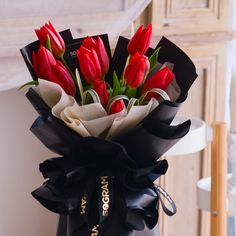 a bouquet of red tulips wrapped in black ribbon