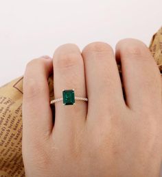 a woman's hand with a ring on it and an emerald stone in the middle